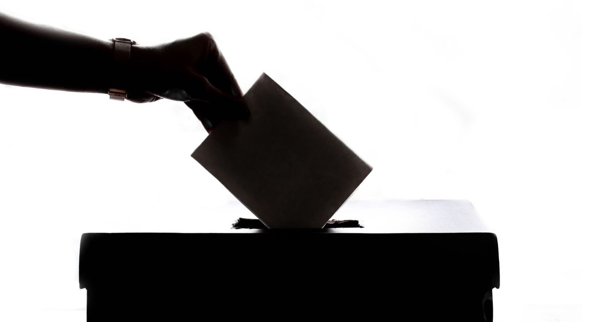 Silhouette of a hand casting a vote into a ballot box